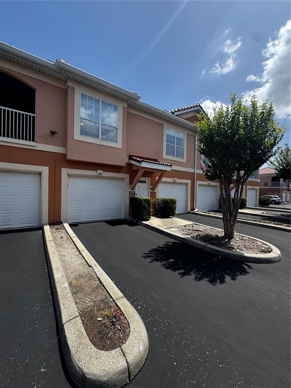 The exterior of a multi-story townhouse features a garage, a small front garden, and a tree — 5000 CULBREATH KEY WAY UNIT 3-301, TAMPA, FL