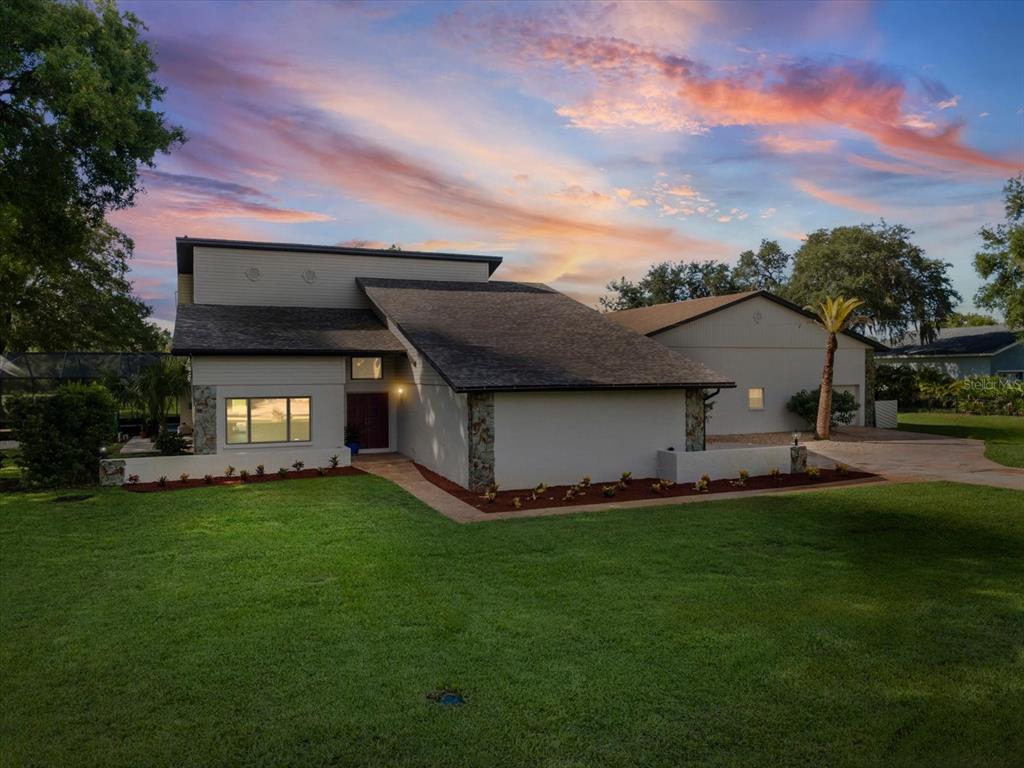 A modern two-story house with a large lawn, stone accents, and a detached garage — 8720 AIRWAY BOULEVARD, NEW PORT RICHEY, FL