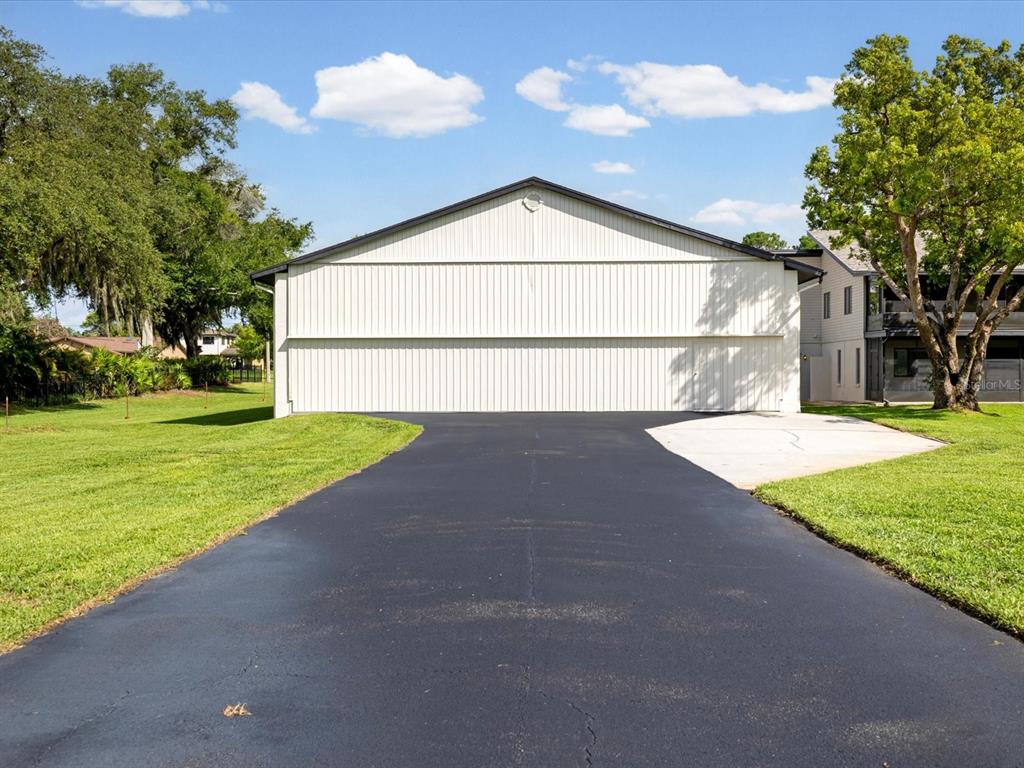 A large metal hangar building stands at the end of a paved asphalt driveway — 8720 AIRWAY BOULEVARD, NEW PORT RICHEY, FL