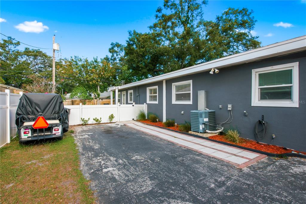 A gray house exterior with a paved driveway, white fence, and a covered utility trailer — 536 PATRICIA AVENUE, DUNEDIN, FL