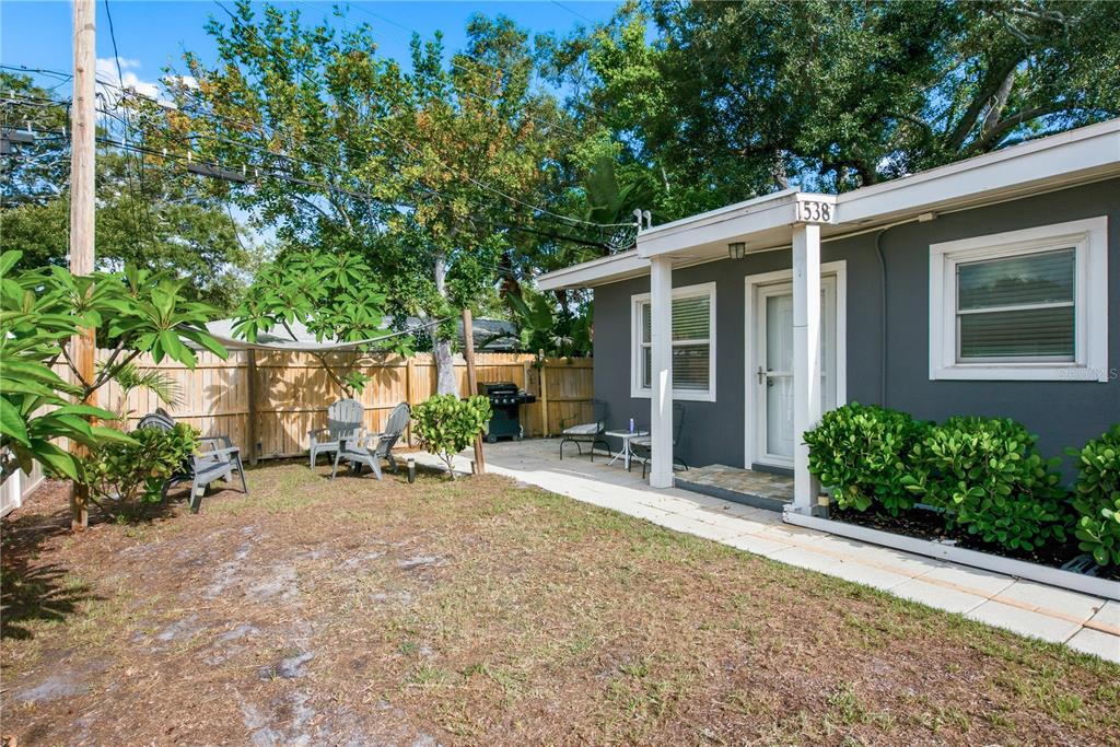 A gray house exterior features a small covered porch, a patio, and a fenced yard — 536 PATRICIA AVENUE, DUNEDIN, FL