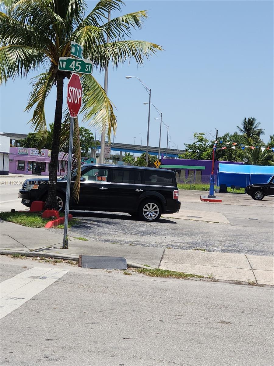 A black SUV is parked on a paved lot near a stop sign and palm tree — 4420 NW 7th Ave, Miami FL 33127, MIAMI, FL