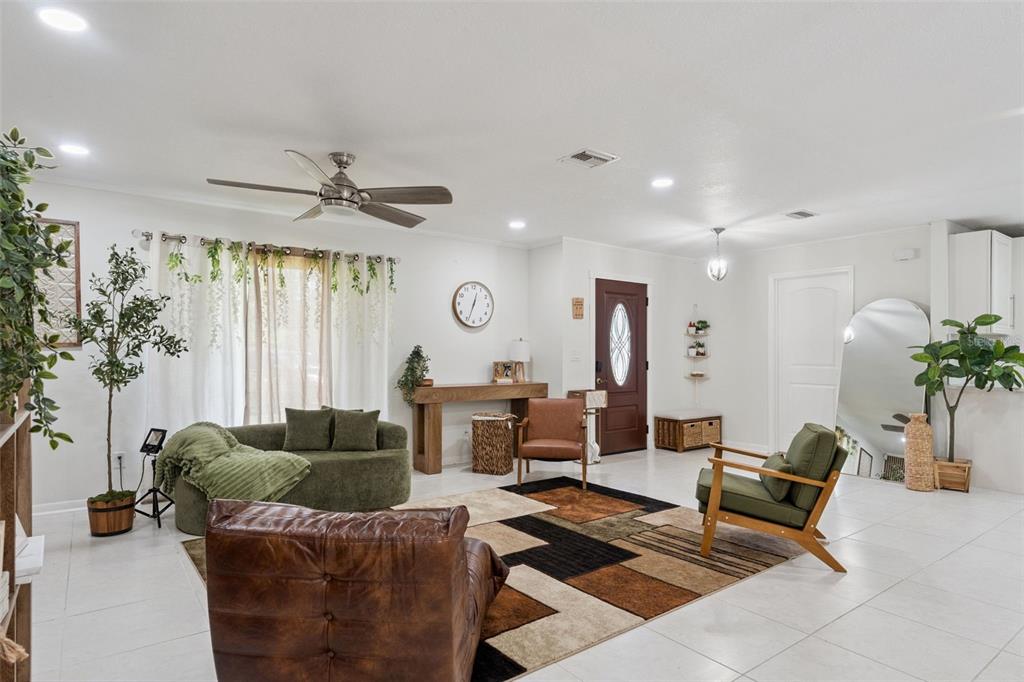 A living room features a geometric rug, green and brown seating, and a front door — 1756 TANGLE WOOD DRIVE, KISSIMMEE, FL