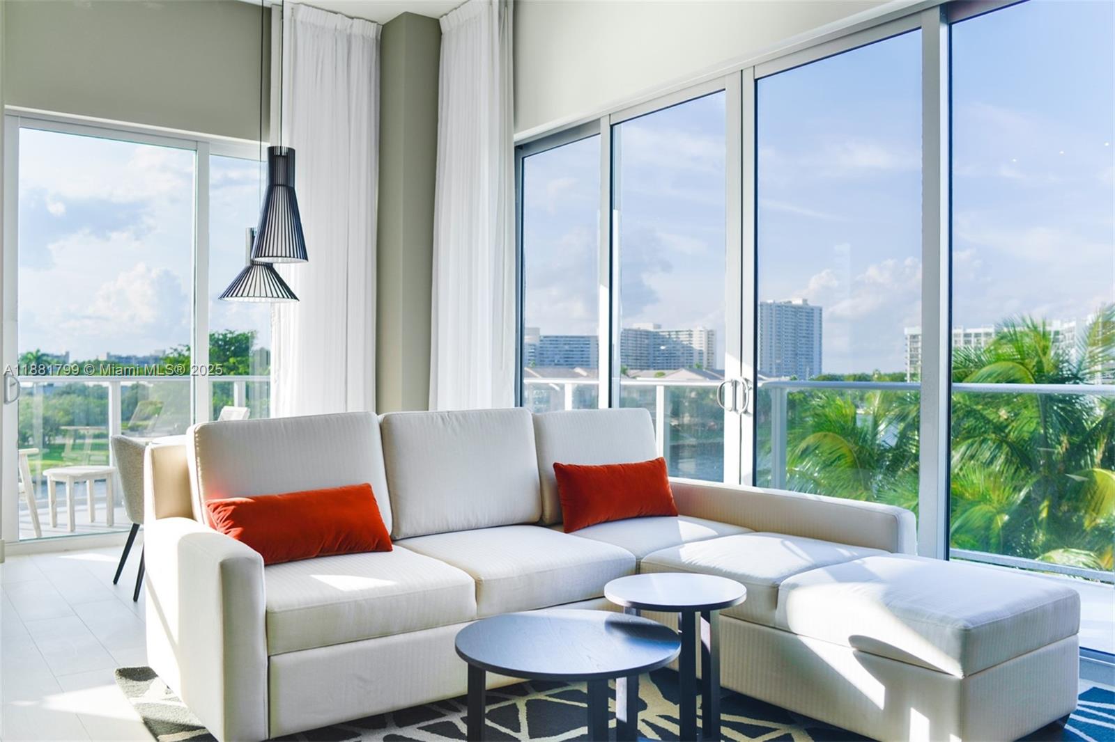A living room features a white sectional sofa, two round tables, and floor-to-ceiling windows — 4010 S Ocean Dr # R302, Hollywood FL 33019, HOLLYWOOD, FL