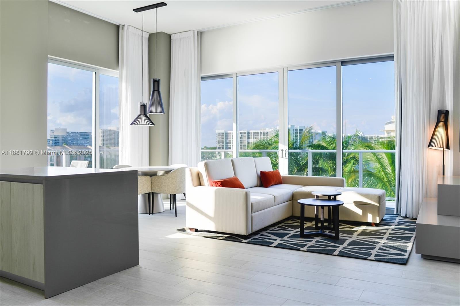 A modern living room features a white sectional sofa, a patterned rug, and floor-to-ceiling windows — 4010 S Ocean Dr # R302, Hollywood FL 33019, HOLLYWOOD, FL