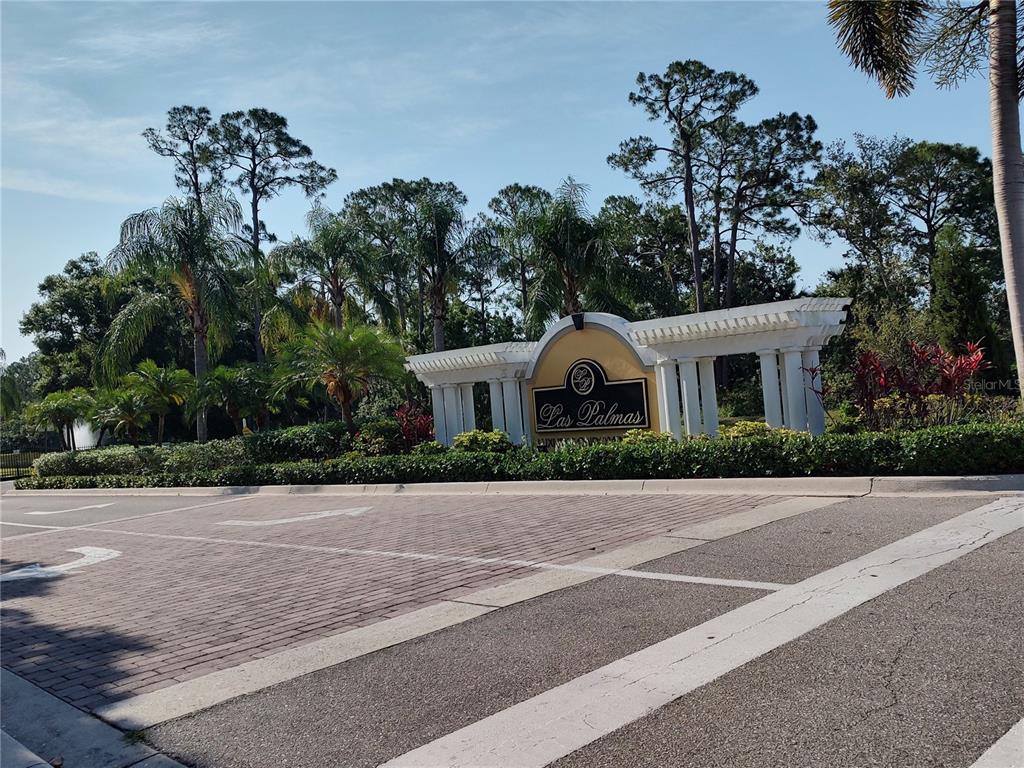 The entrance sign for Las Palmas features a white architectural structure surrounded by palm trees — 5600 BENTGRASS DRIVE UNIT 8-103, SARASOTA, FL