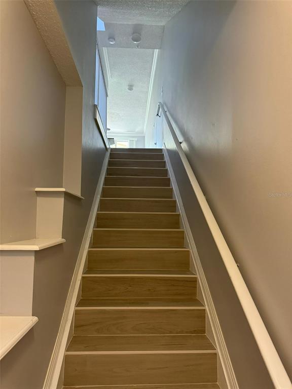 A straight staircase with light wood-look treads leads upward between two gray walls — 5600 BENTGRASS DRIVE UNIT 8-103, SARASOTA, FL