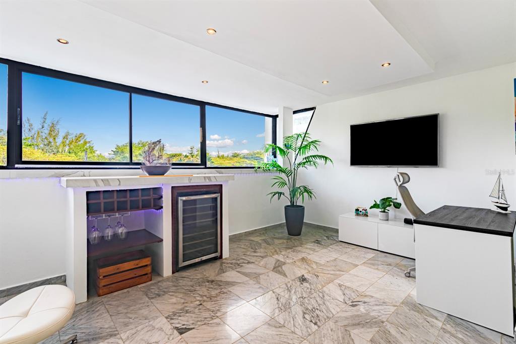 A modern office space features a wine cooler, marble tile flooring, and large windows — 7185 COND. MAR DE ISLA VERDE UNIT 3A, CAROLINA, PR