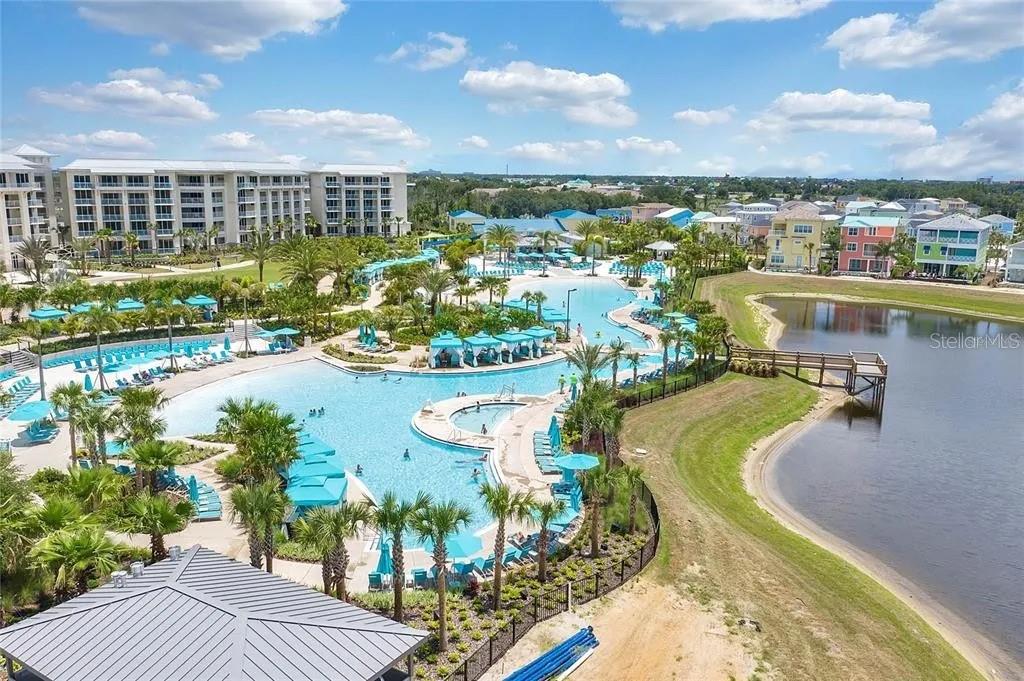 An aerial view of a resort-style swimming pool complex next to a lake and buildings — 2960 SALTED RIM ROAD, KISSIMMEE, FL