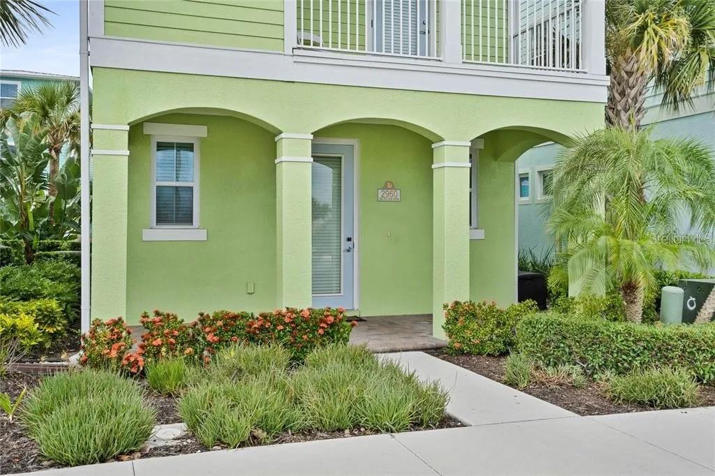 The exterior of a light green house features a covered porch with arched columns — 2960 SALTED RIM ROAD, KISSIMMEE, FL