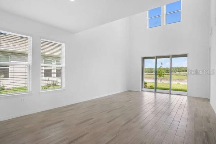 An empty living room features high ceilings, light wood-look flooring, and large sliding glass doors — 1032 TOP MINNOW ROAD, ST CLOUD, FL