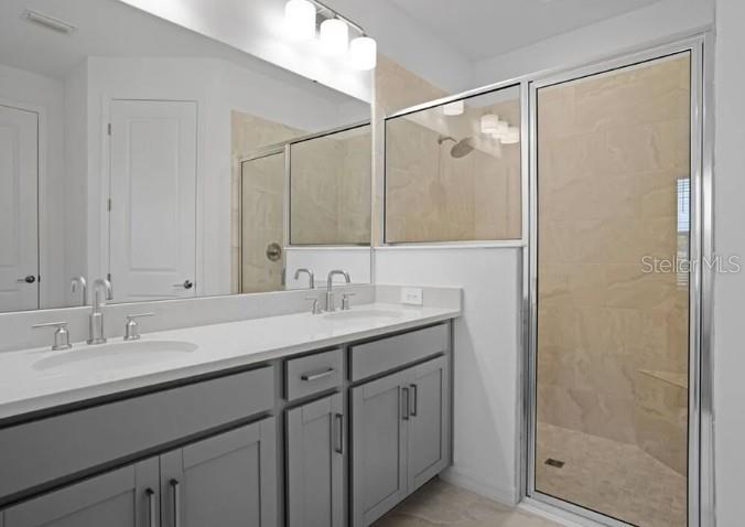 A bathroom features a gray double vanity with a large mirror and a glass-enclosed shower — 1032 TOP MINNOW ROAD, ST CLOUD, FL