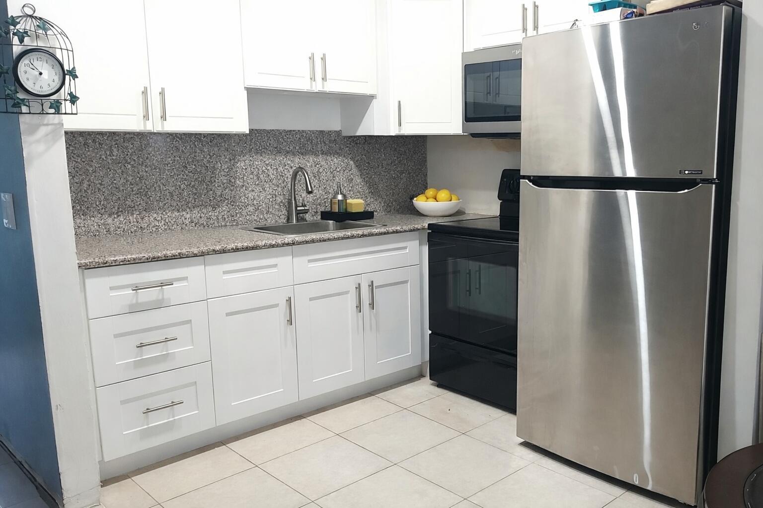 A kitchen features white cabinets, granite countertops, a stainless steel refrigerator, and black appliances — 330 Brighton H, Boca Raton FL 33434, BOCA RATON, FL
