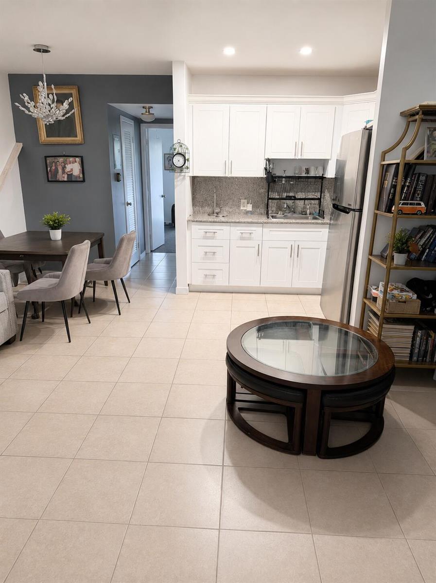 A kitchen with white cabinets and a dining area with a dark accent wall — 330 Brighton H, Boca Raton FL 33434, BOCA RATON, FL