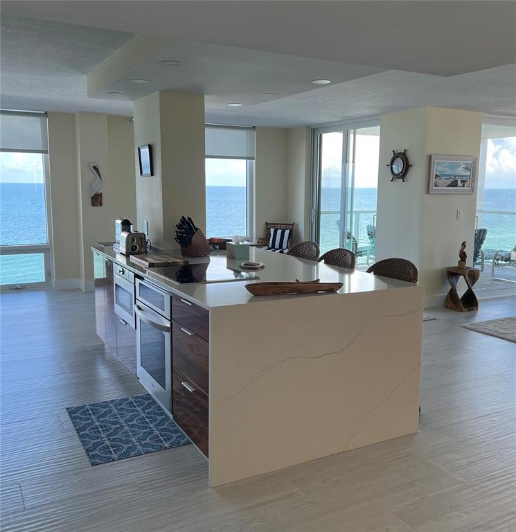 A modern kitchen island with a quartz countertop sits in an open-concept room overlooking the ocean — 2425 GULF OF MEXICO DRIVE UNIT 11F, LONGBOAT KEY, FL
