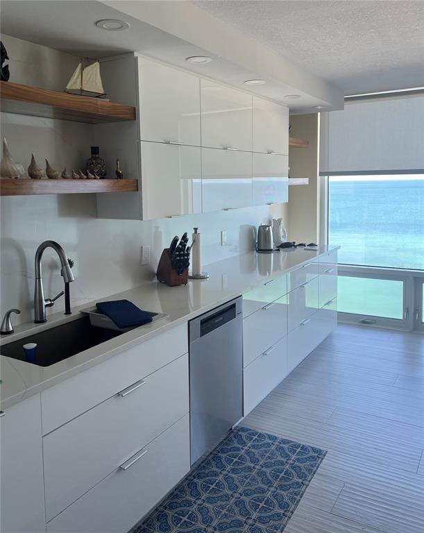 A modern kitchen features white glossy cabinets, wood shelving, and a view of the ocean — 2425 GULF OF MEXICO DRIVE UNIT 11F, LONGBOAT KEY, FL