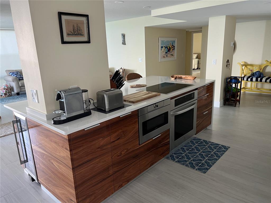 A kitchen island features wood-grain cabinetry, a white countertop, a cooktop, and built-in appliances — 2425 GULF OF MEXICO DRIVE UNIT 11F, LONGBOAT KEY, FL