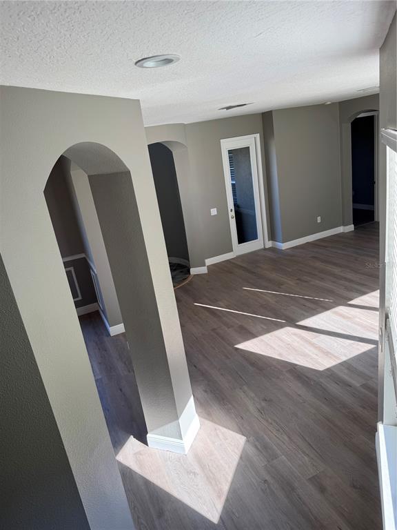 An interior view shows a room with gray walls, wood-look flooring, and arched doorways — 3699 HEIRLOOM ROSE PLACE, OVIEDO, FL