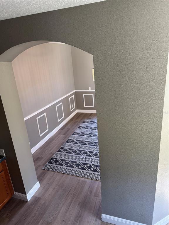 An arched doorway leads into a room with gray walls, white wainscoting, and wood flooring — 3699 HEIRLOOM ROSE PLACE, OVIEDO, FL