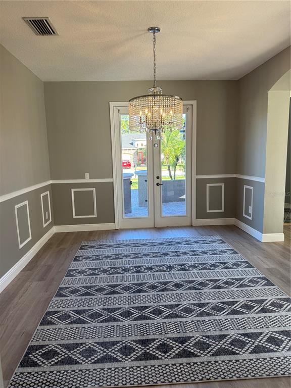 A dining room features gray walls with white wainscoting, a crystal chandelier, and a patterned rug — 3699 HEIRLOOM ROSE PLACE, OVIEDO, FL