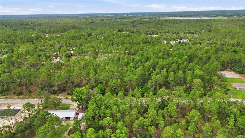An aerial view shows a wooded lot with a small building and a paved road — 0000 SW BEAVER DRIVE, DUNNELLON, FL