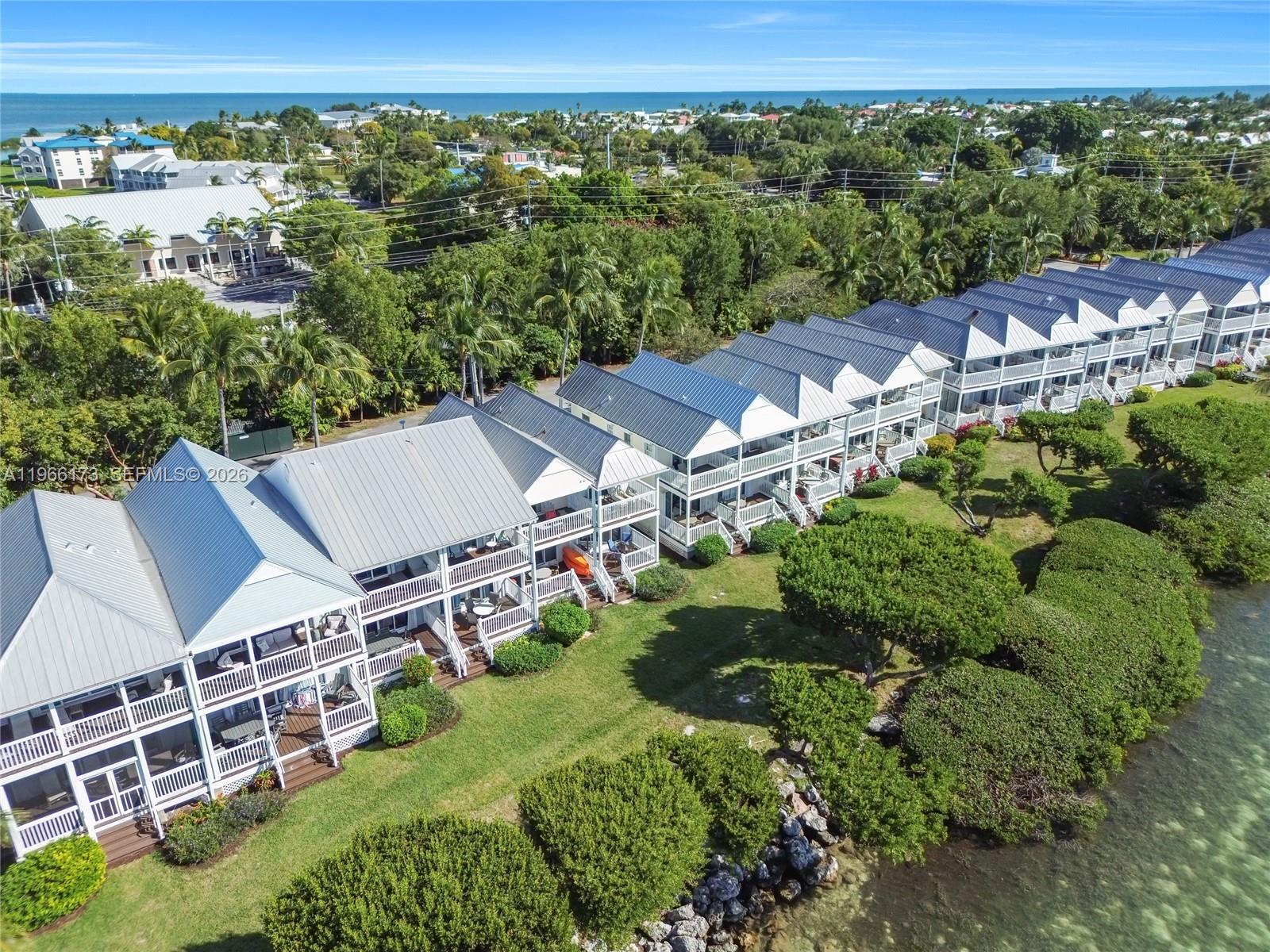 An aerial view shows a row of multi-story waterfront townhomes with metal roofs — 5036 Sunset Village Dr, Duck FL 33050, DUCK, FL