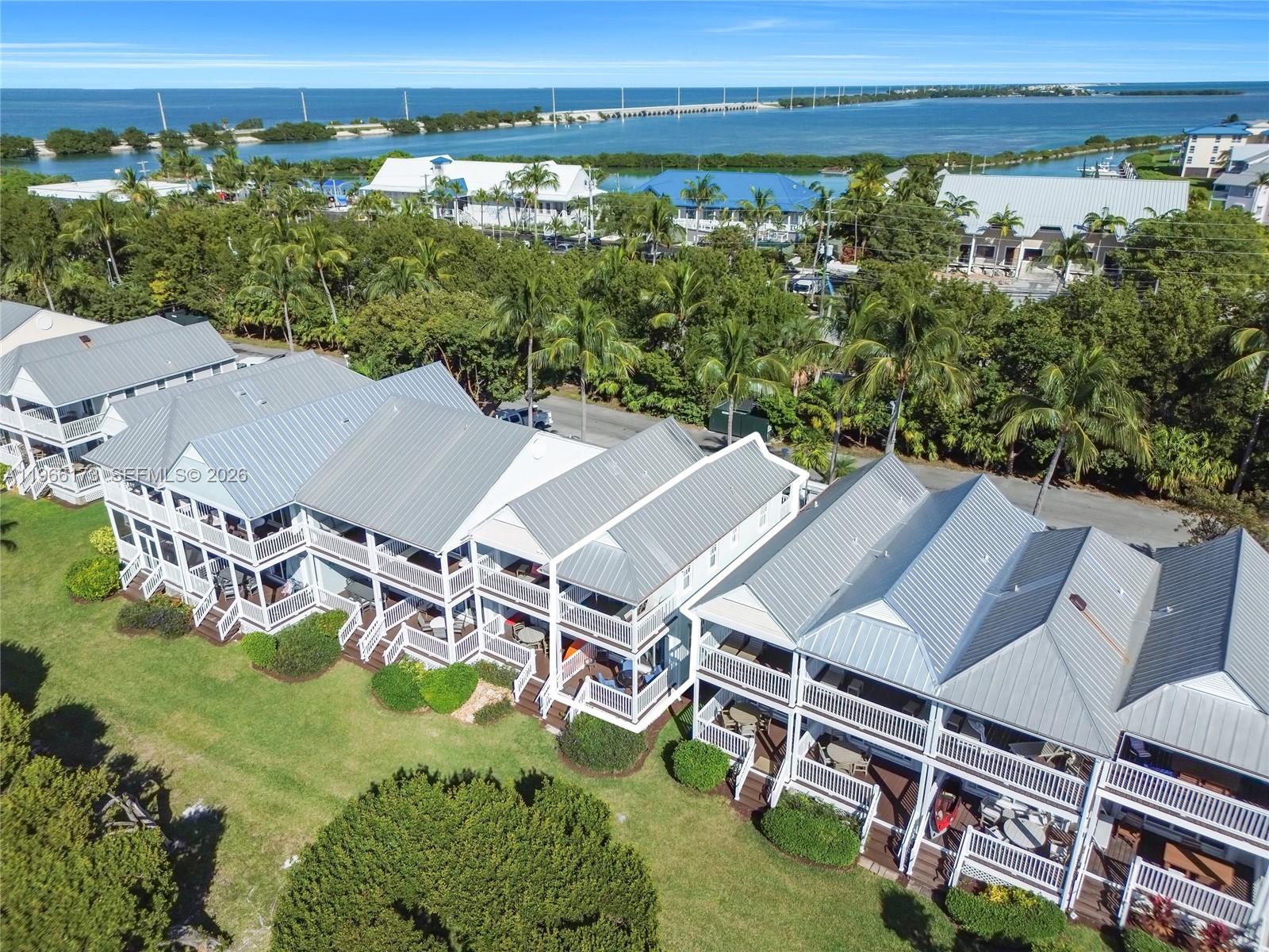 An aerial view shows a row of multi-story houses with metal roofs and balconies — 5036 Sunset Village Dr, Duck FL 33050, DUCK, FL