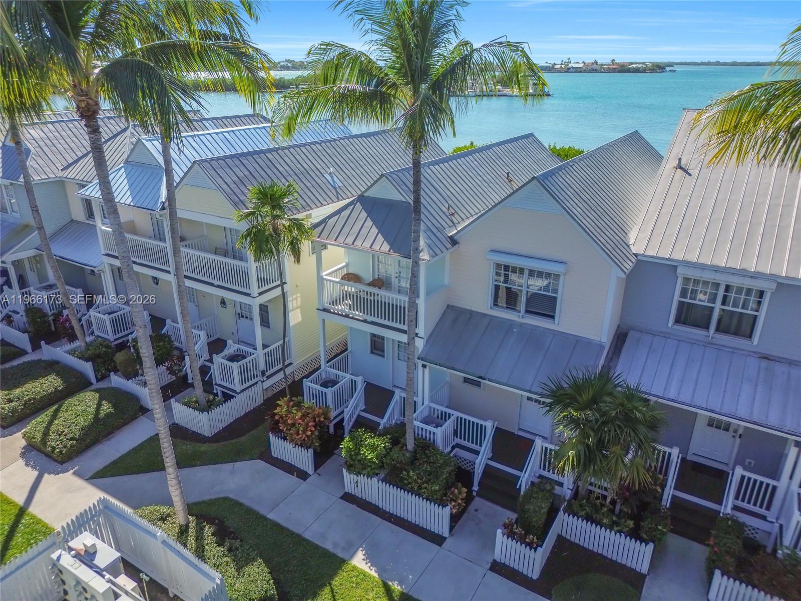 An aerial view shows a row of coastal townhouses with metal roofs and white balconies — 5036 Sunset Village Dr, Duck FL 33050, DUCK, FL
