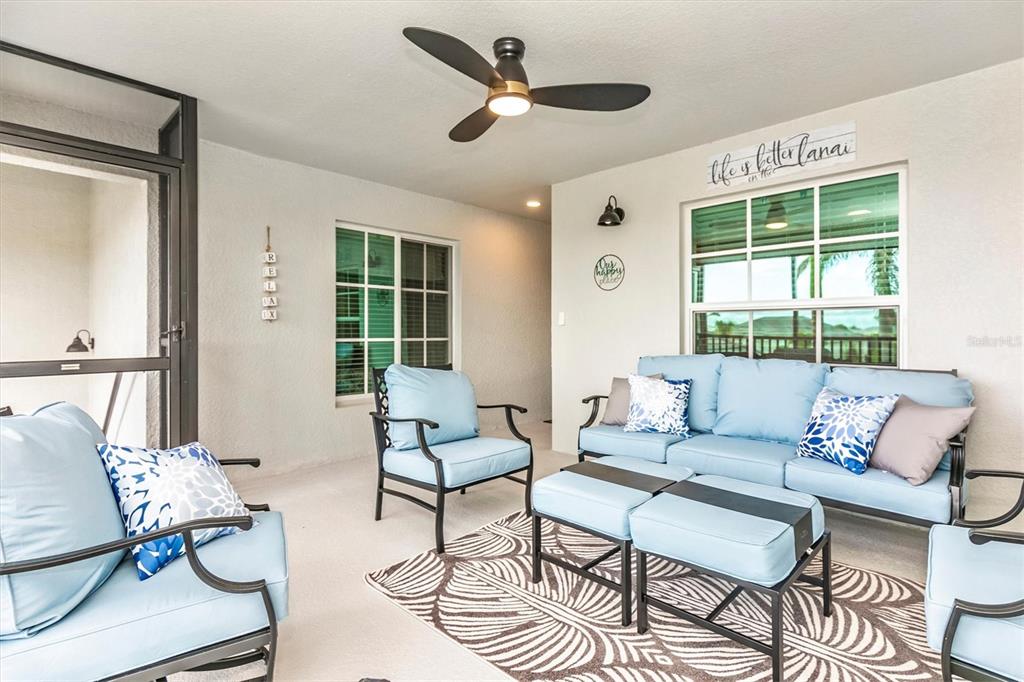 A covered patio features light blue outdoor furniture, a ceiling fan, and a patterned rug — 12550 GALAPAGOS STREET UNIT 204, VENICE, FL