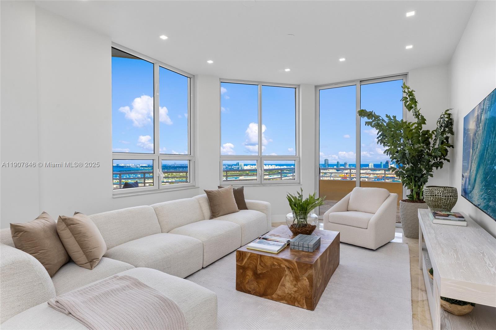 A bright living room features a white sectional sofa, wooden coffee table, and floor-to-ceiling windows — 808 Brickell Key Dr # 3901, Miami FL 33131, MIAMI, FL