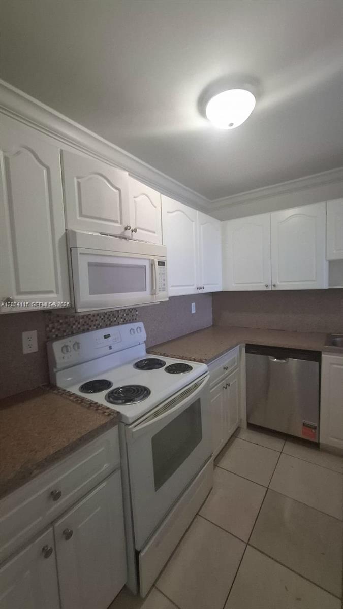 A kitchen features white cabinets, a white stove, a microwave, and a stainless steel dishwasher — 6940 Miami Gardens Dr # 522, Hialeah FL 33015, HIALEAH, FL