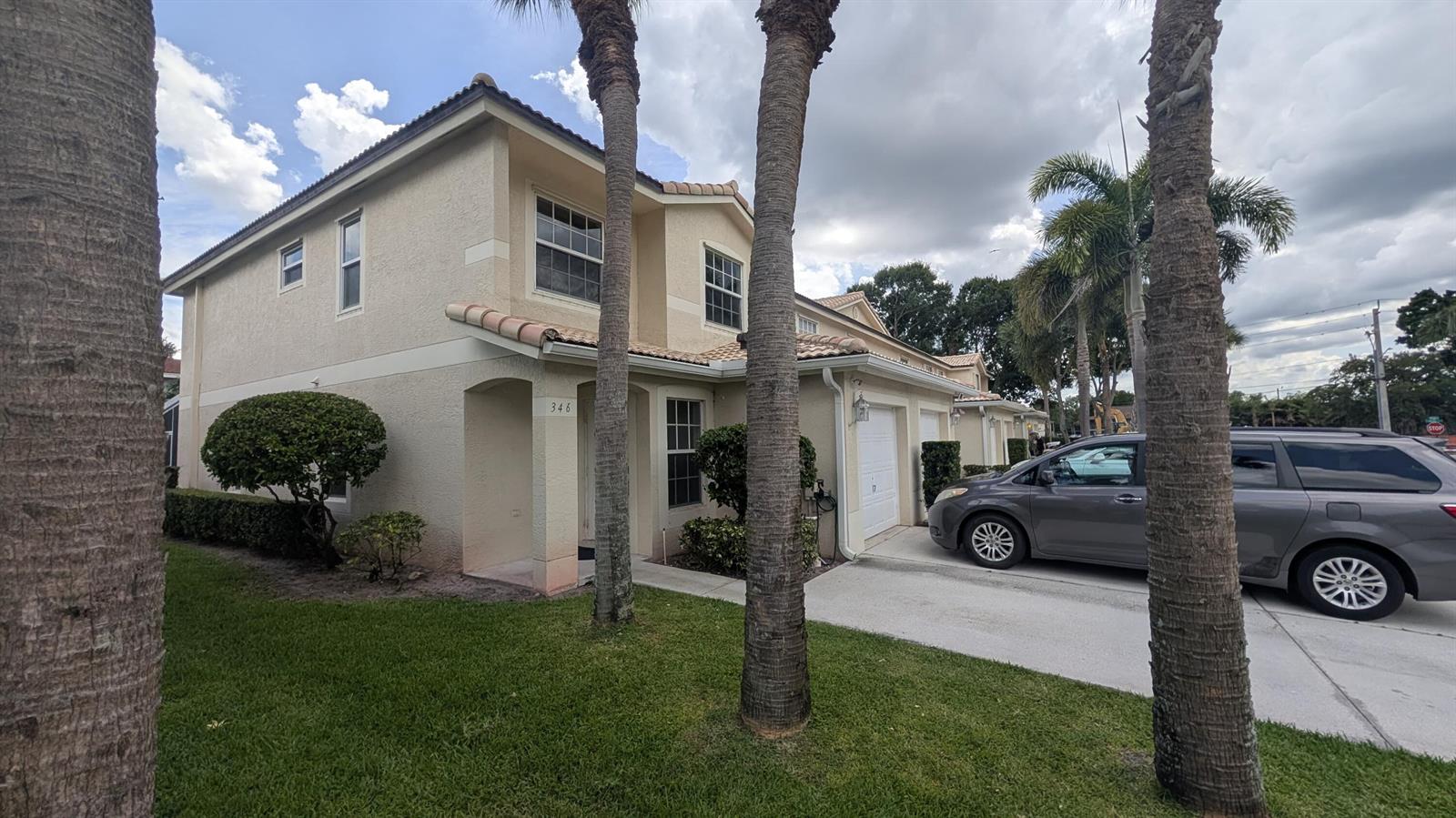 A two-story tan stucco townhouse with a garage, palm trees, and a parked minivan — 346 Timberwalk Trail, Jupiter FL 33458, JUPITER, FL