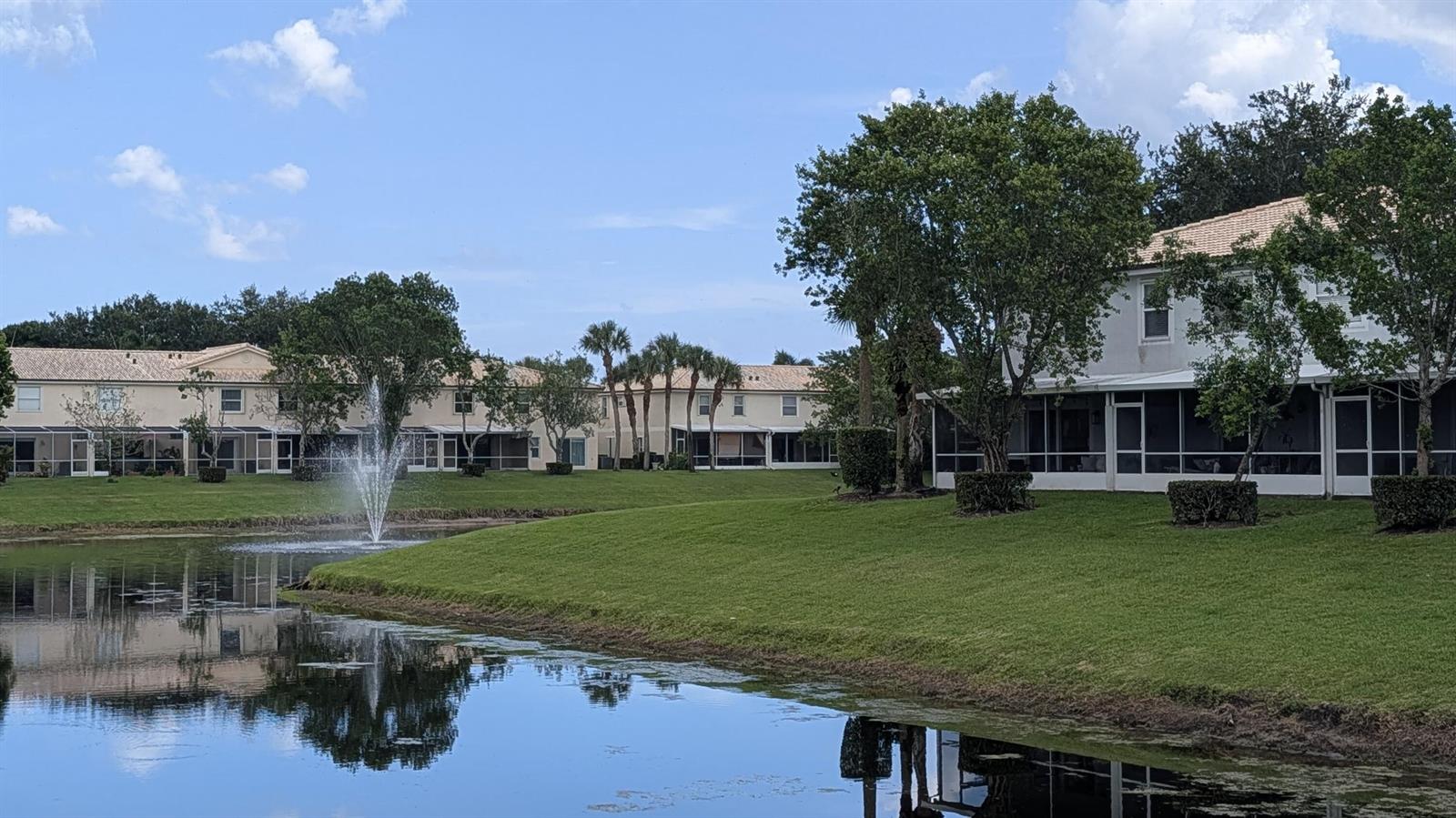 A pond with a fountain sits in front of two-story townhomes with screened lanais — 346 Timberwalk Trail, Jupiter FL 33458, JUPITER, FL