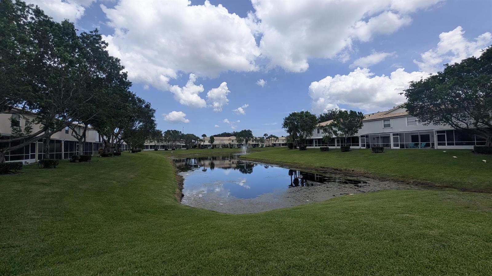 A pond sits between two rows of residential buildings with screened-in patios and green lawns — 346 Timberwalk Trail, Jupiter FL 33458, JUPITER, FL
