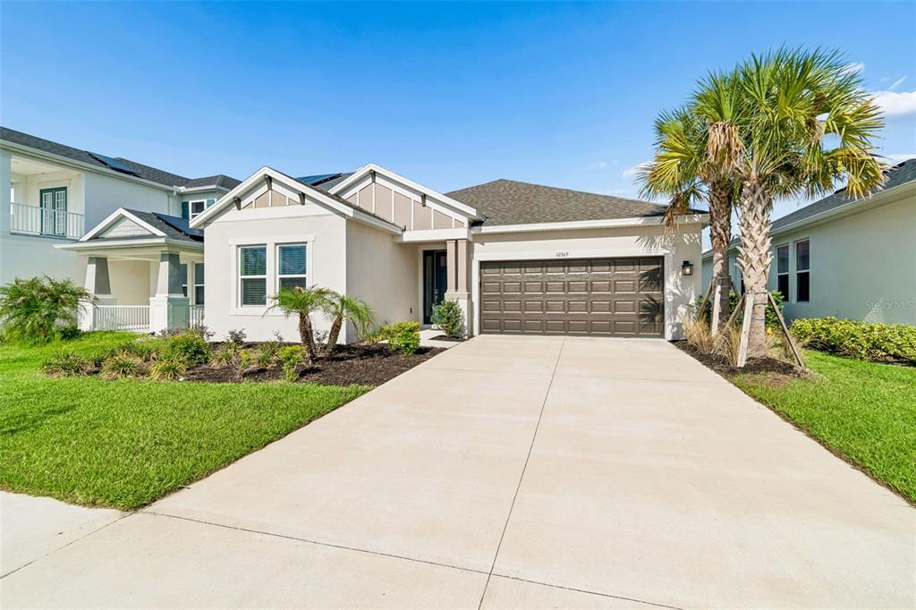A single-story house with a beige stucco exterior, a brown garage door, and a palm tree — 10569 TRANQUIL MEADOW LOOP, RIVERVIEW, FL