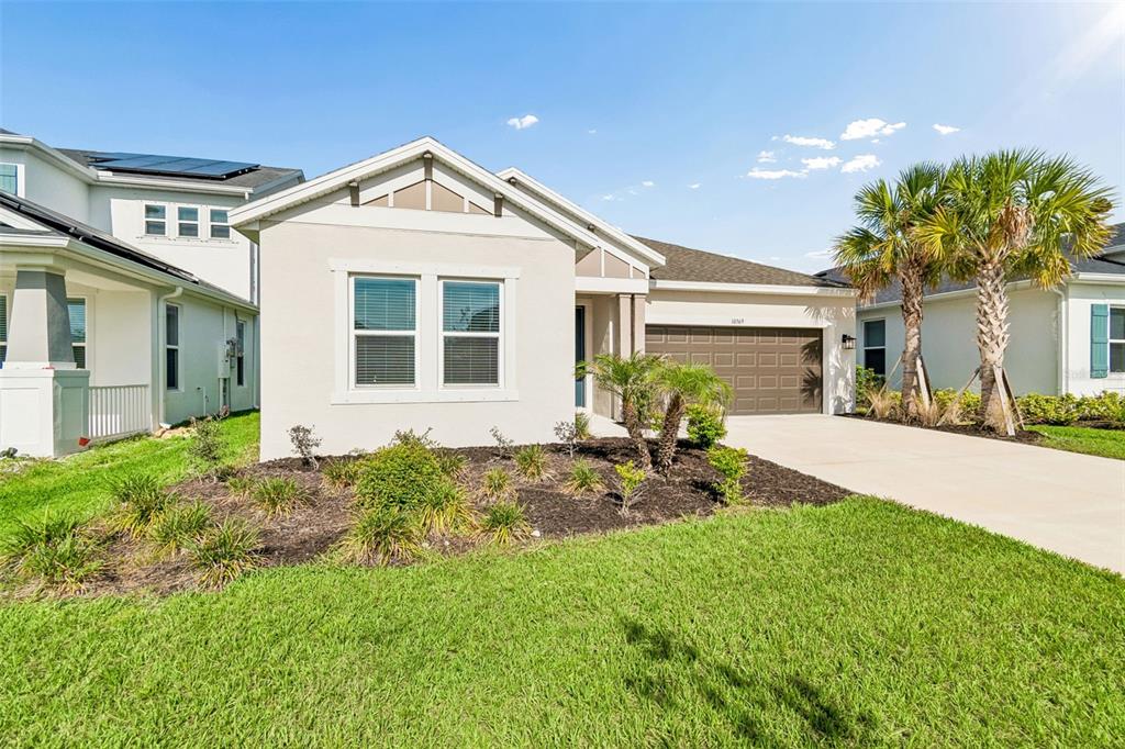 A single-story house with a beige stucco exterior, a two-car garage, and a front lawn — 10569 TRANQUIL MEADOW LOOP, RIVERVIEW, FL