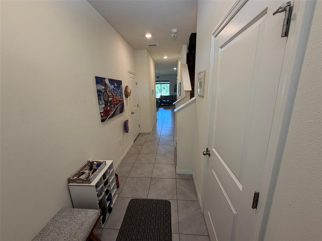 A tiled hallway leads from an entryway toward a living area with a staircase nearby — 8860 MILESTONE DRIVE, SARASOTA, FL