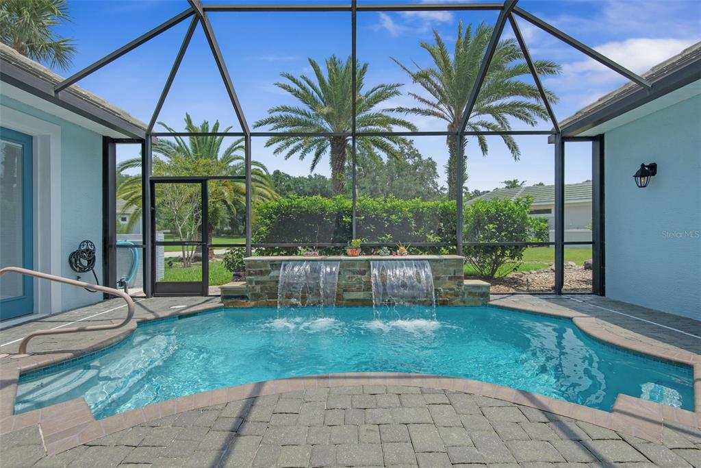 A screened-in patio features a small pool with a stone water feature and palm trees — 27 LONGVIEW WAY N, PALM COAST, FL