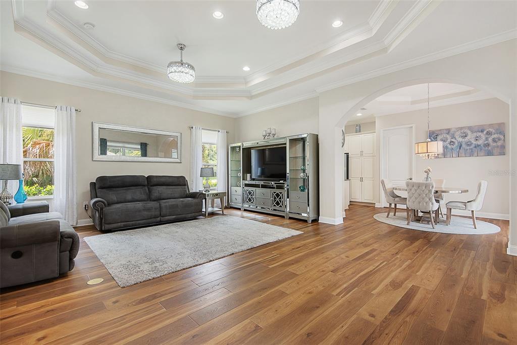 A living room with wood floors, a tray ceiling, and an adjacent dining area — 27 LONGVIEW WAY N, PALM COAST, FL
