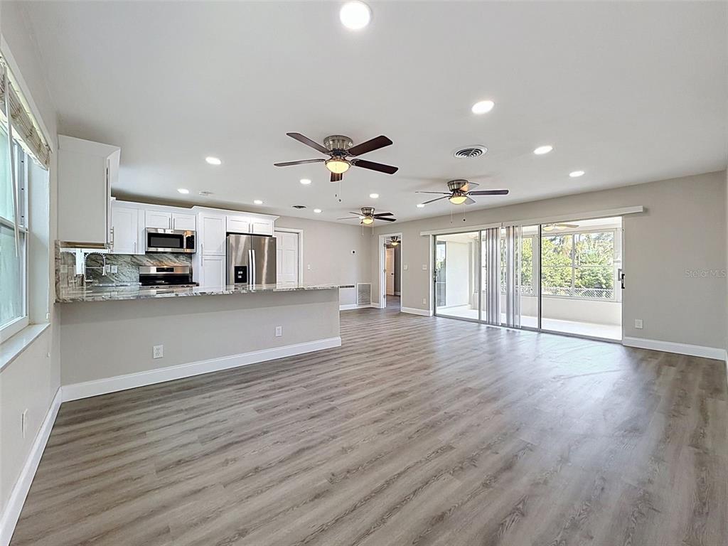 A kitchen with white cabinets and granite countertops opens to a spacious living area — 307 87TH AVENUE NE, ST PETERSBURG, FL