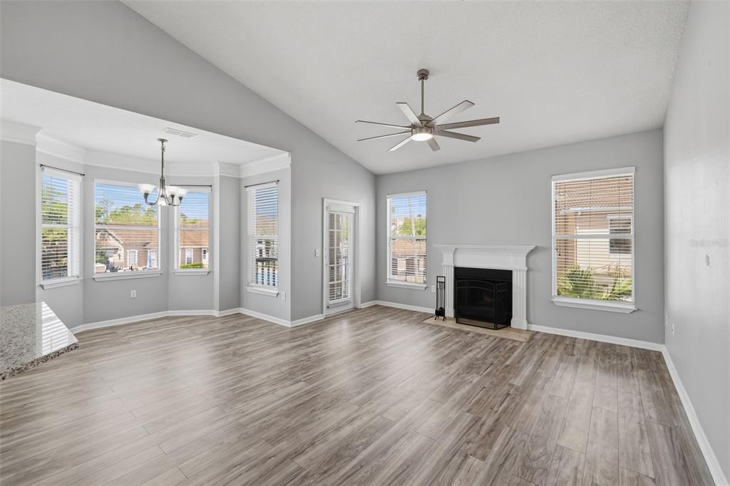 A living room with light wood-look flooring, a fireplace, a ceiling fan, and large windows — 10504 VILLA VIEW CIRCLE, TAMPA, FL