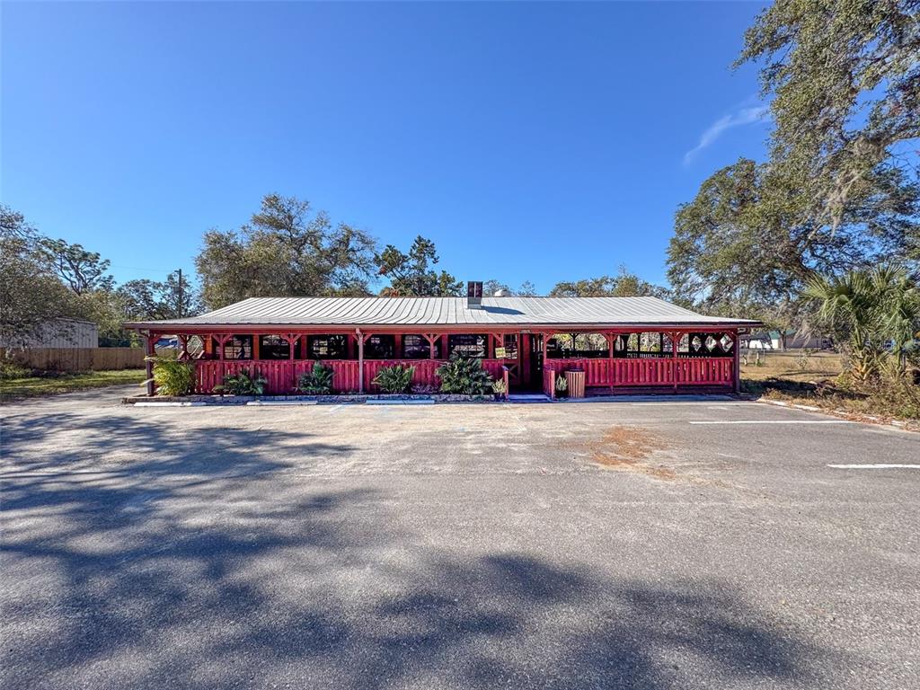 A red, single-story building with a metal roof and a covered porch sits on asphalt — 15525 & 15527 SHADY HILLS ROAD, SHADY HILLS, FL