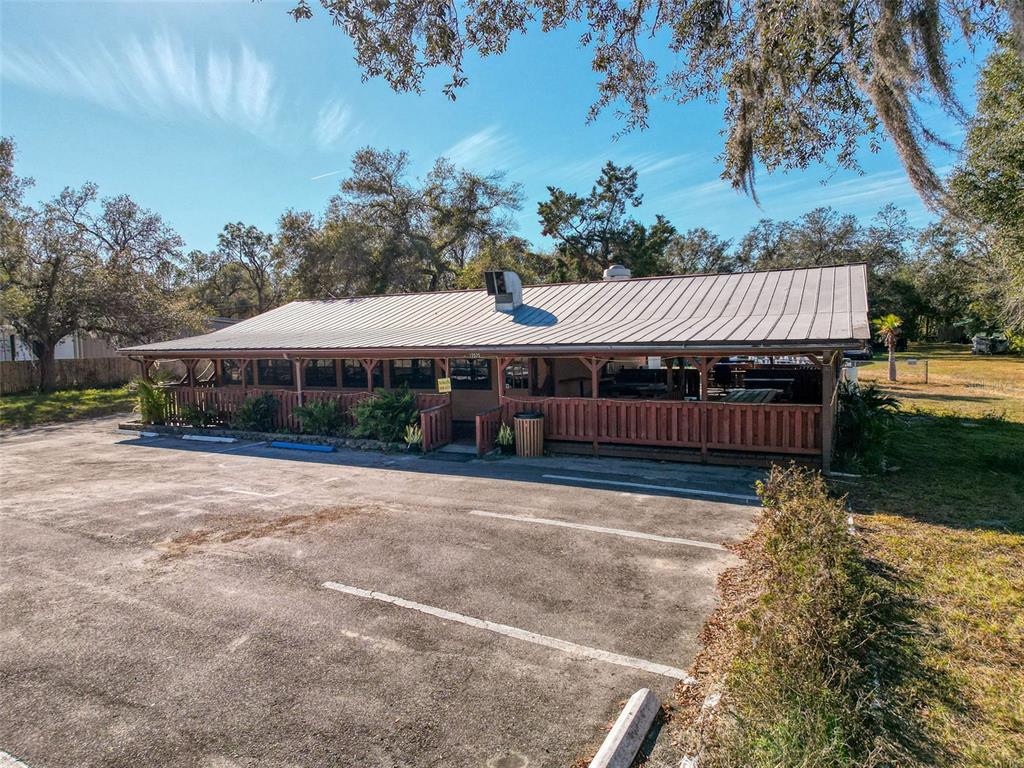 A single-story commercial building with a metal roof and a wooden porch faces a parking lot — 15525 & 15527 SHADY HILLS ROAD, SHADY HILLS, FL