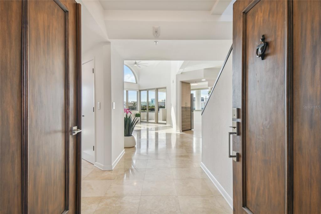 A view through an open wooden doorway into a bright foyer with tiled flooring — 941 SEDDON COVE WAY, TAMPA, FL