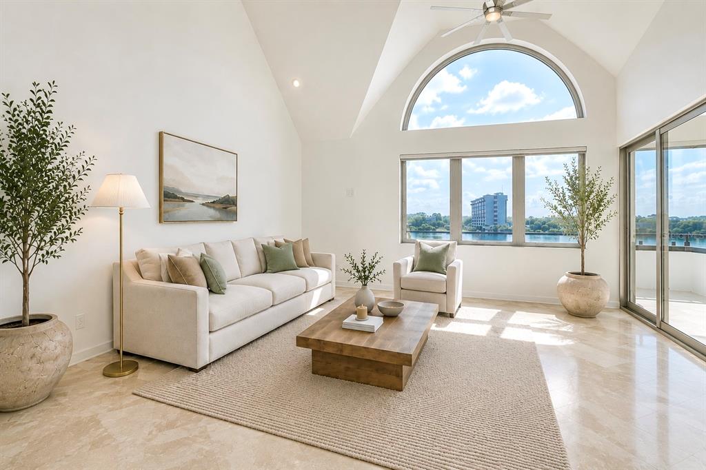 A bright living room features a vaulted ceiling, large arched window, and neutral furniture — 941 SEDDON COVE WAY, TAMPA, FL