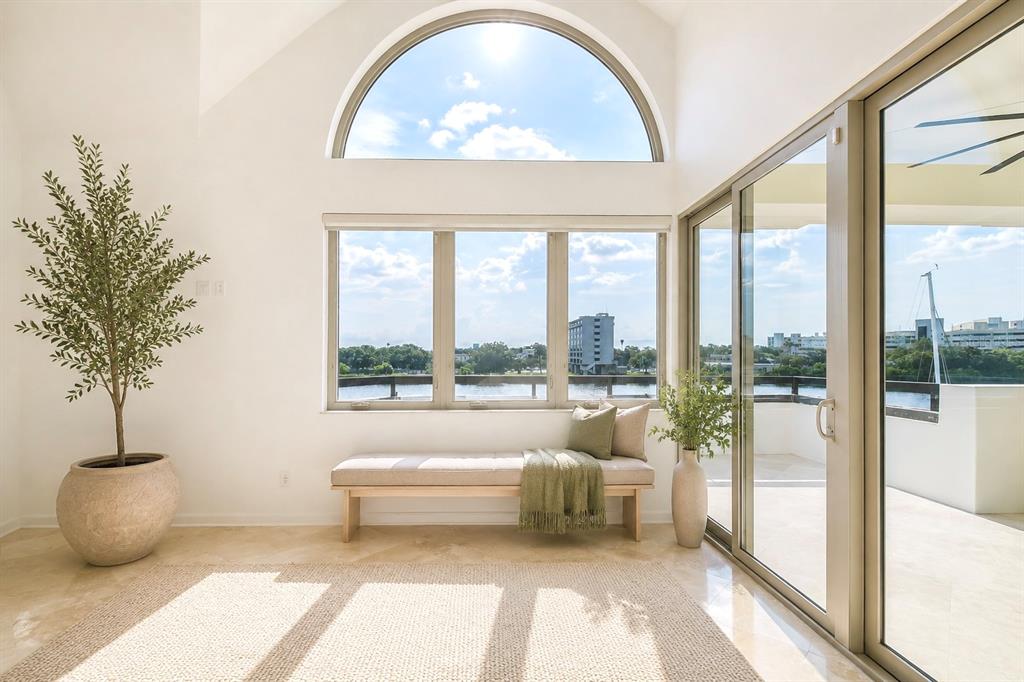 A sunlit room features a bench under a large window, a potted tree, and balcony access — 941 SEDDON COVE WAY, TAMPA, FL