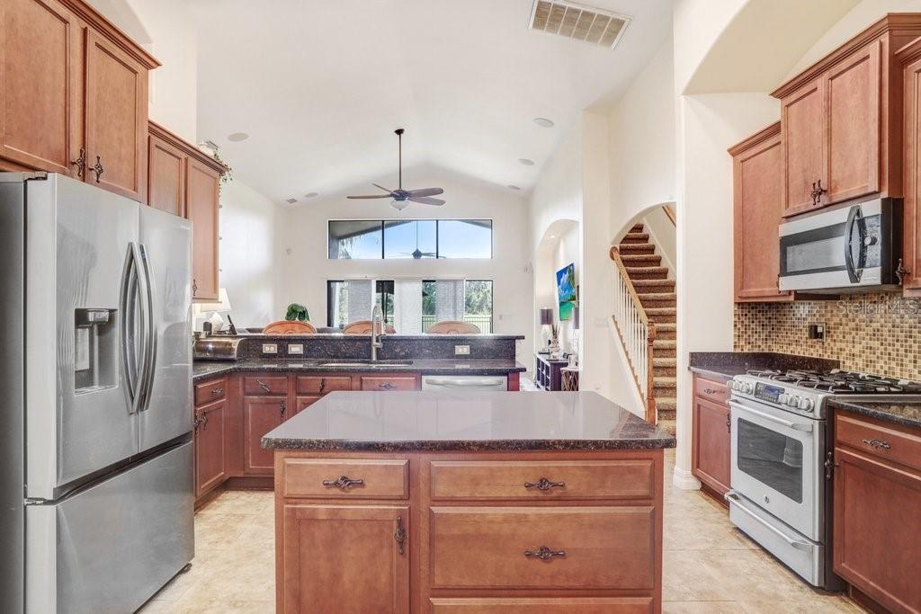 A kitchen with wood cabinets, granite countertops, a center island, and stainless steel appliances — 15723 STARLING WATER DRIVE, LITHIA, FL