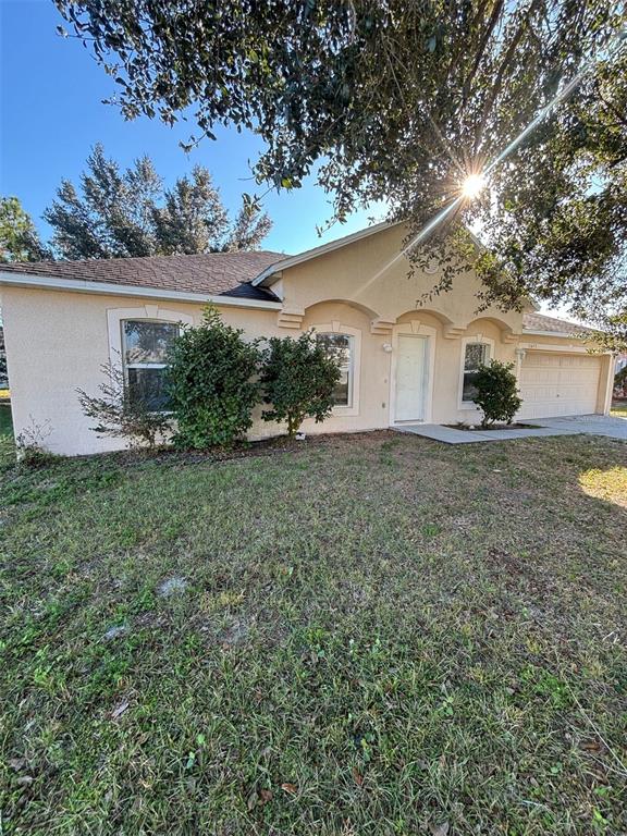 A single-story house with a beige stucco exterior, a garage, and a front yard — 1613 SAIL DRIVE, POINCIANA, FL