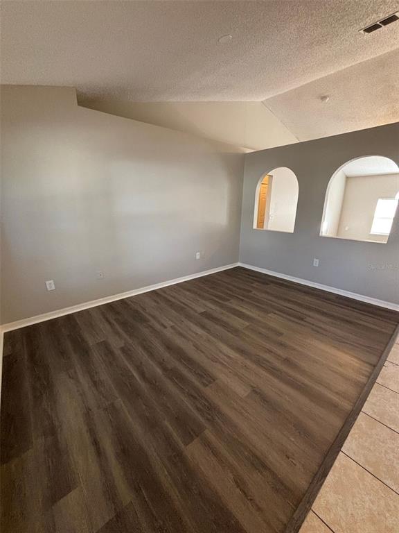 An empty room features wood-look flooring, light gray walls, and two arched wall cutouts — 1613 SAIL DRIVE, POINCIANA, FL