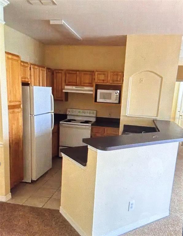 A kitchen features white cabinets, a stainless steel stove, and a gray subway tile backsplash — 6412 QUEENS BOROUGH AVENUE UNIT 315, ORLANDO, FL